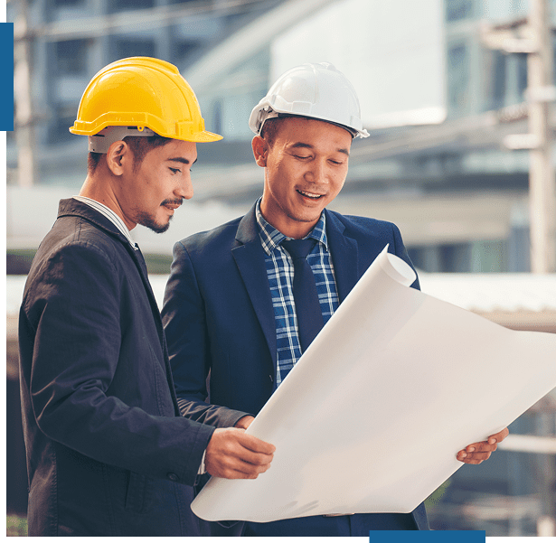 Two construction workers reviewing blueprints at a building site.