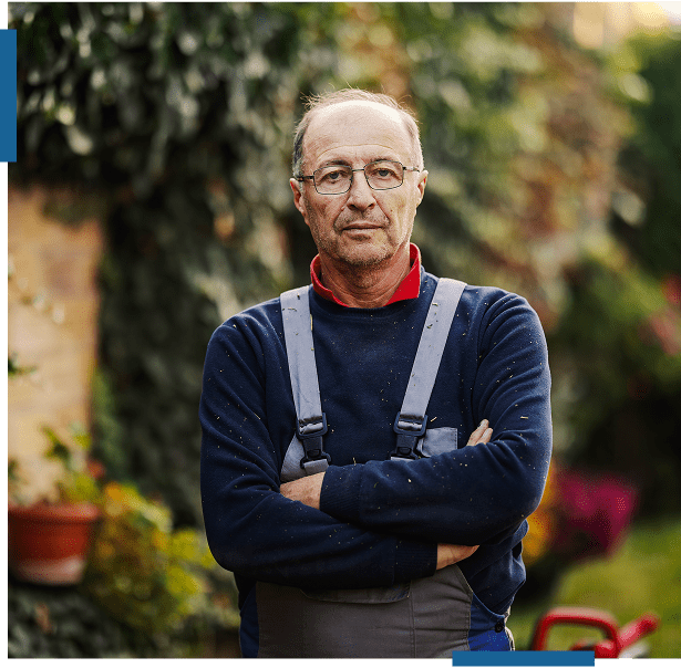 Confident elderly man standing outdoors with arms crossed.